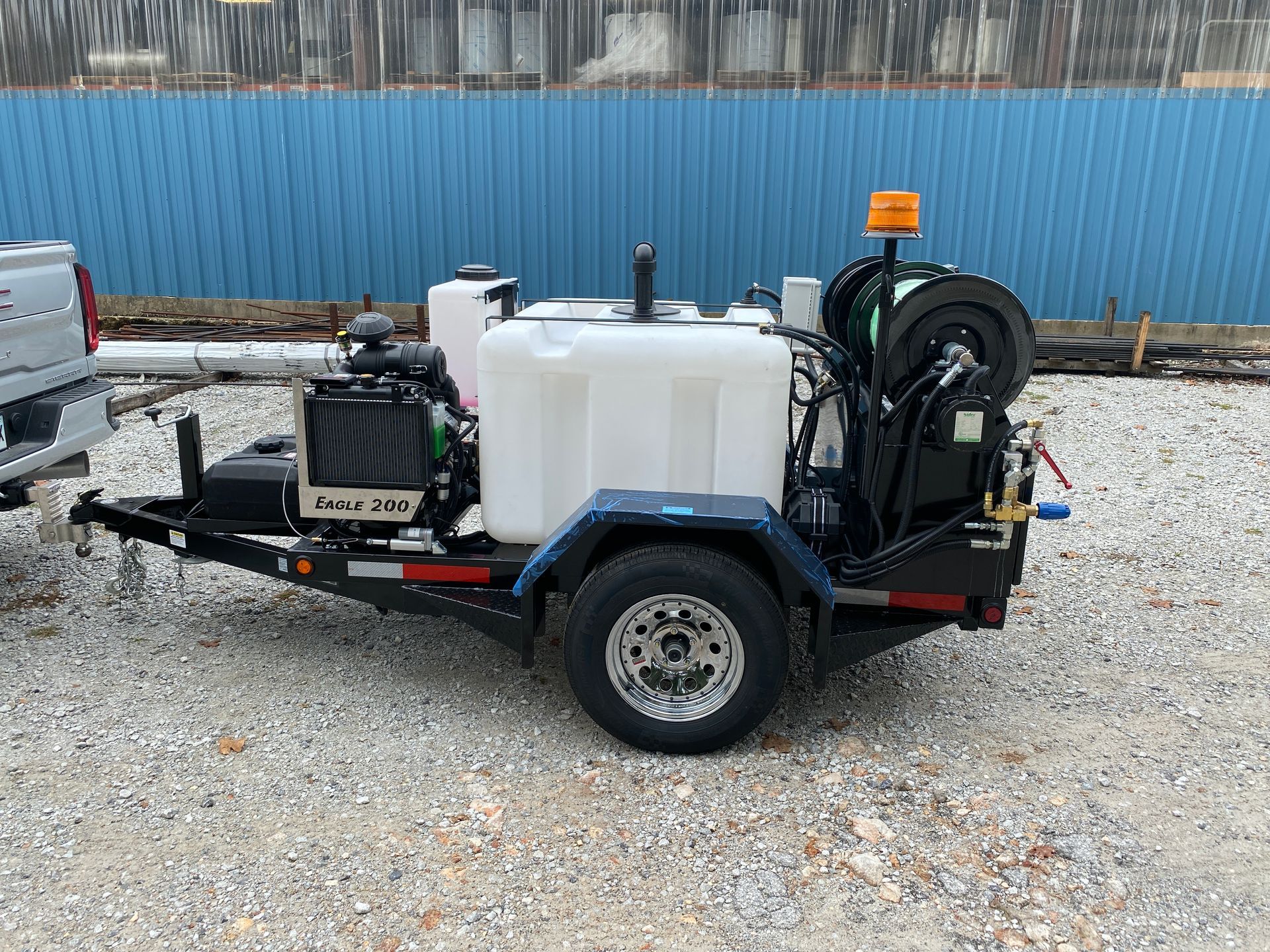 A trailer with a hose attached to it is parked next to a truck