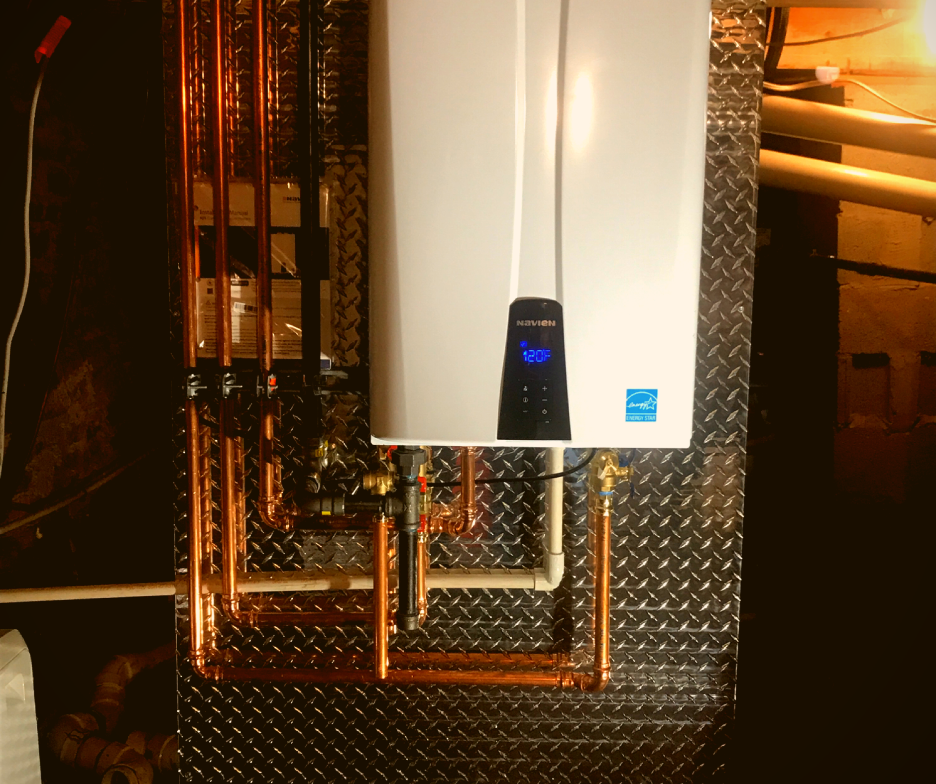 A white water heater is mounted to a metal wall