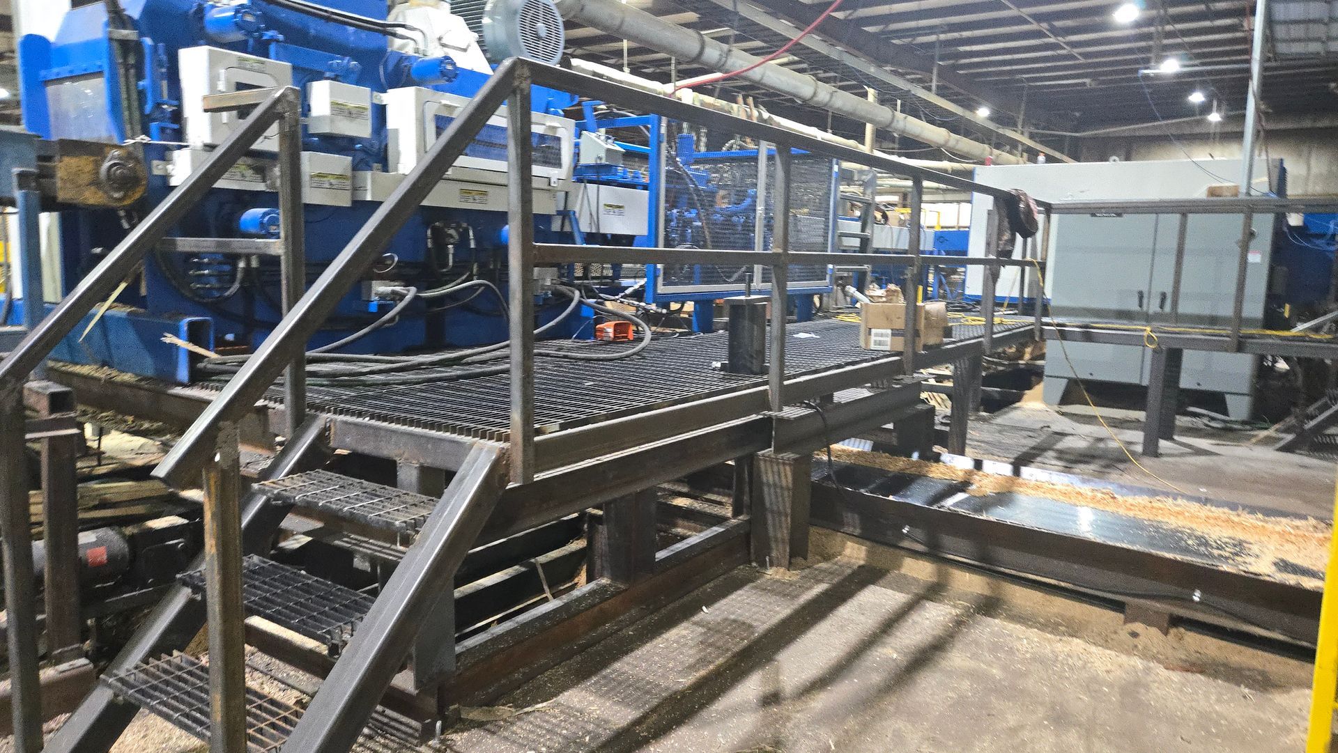 A metal platform with stairs leading up to a machine in a factory.
