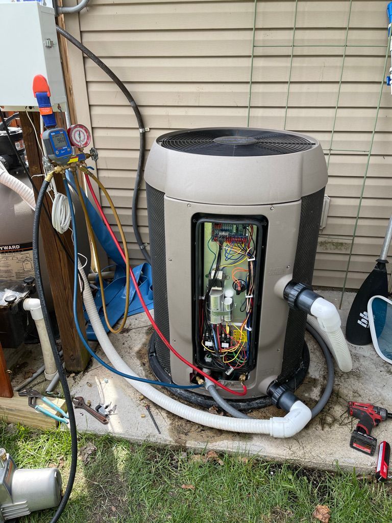 A pool heater is sitting on a sidewalk next to a house.