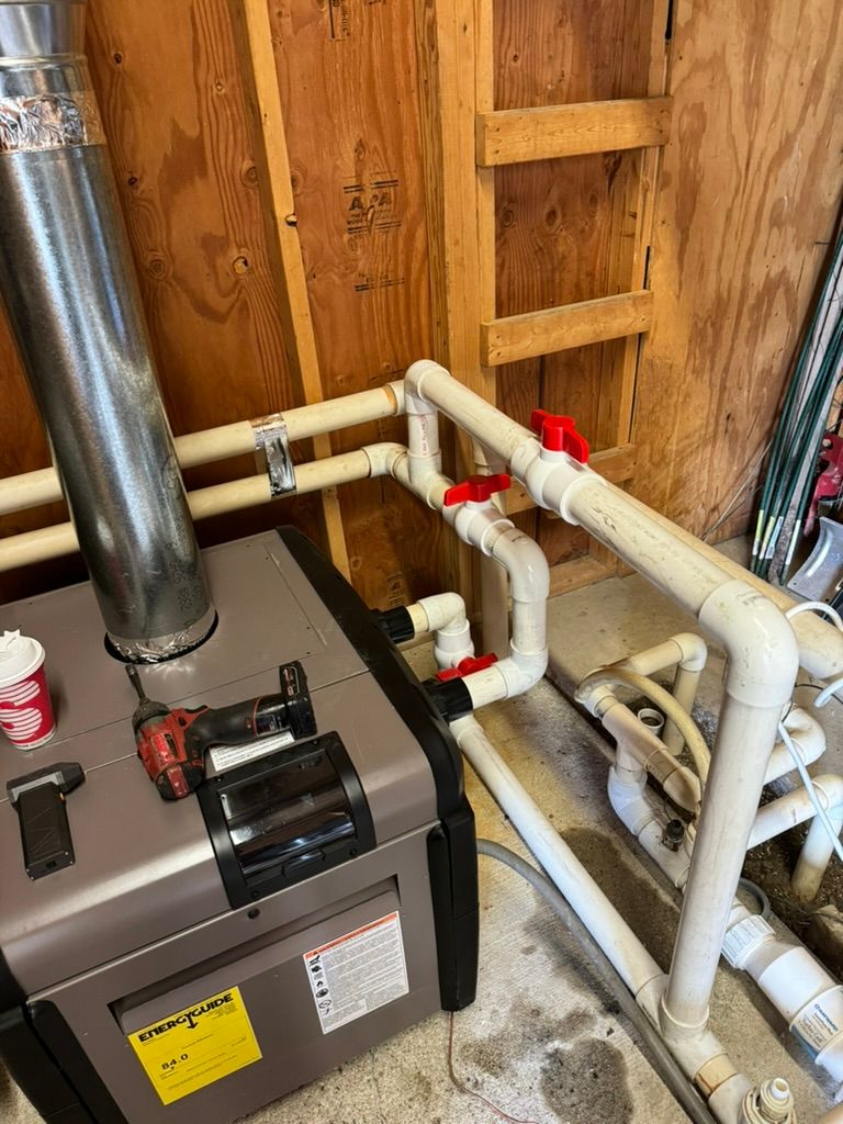 A boiler is sitting next to a bunch of pipes in a room.