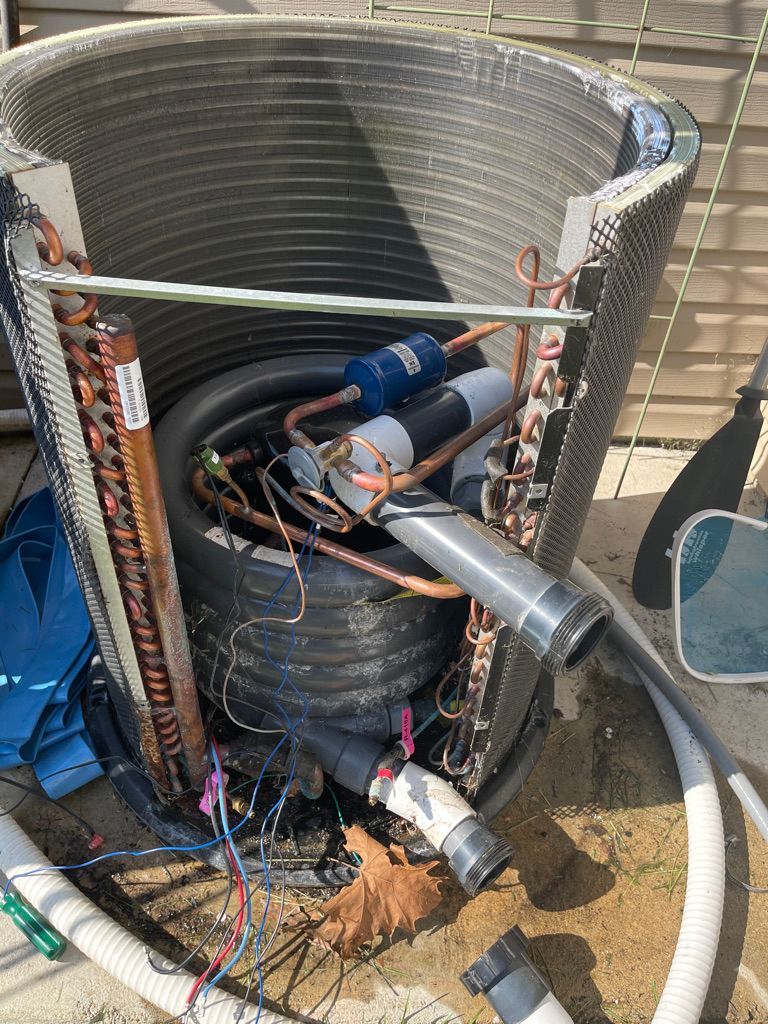 A broken air conditioner is sitting on the ground.