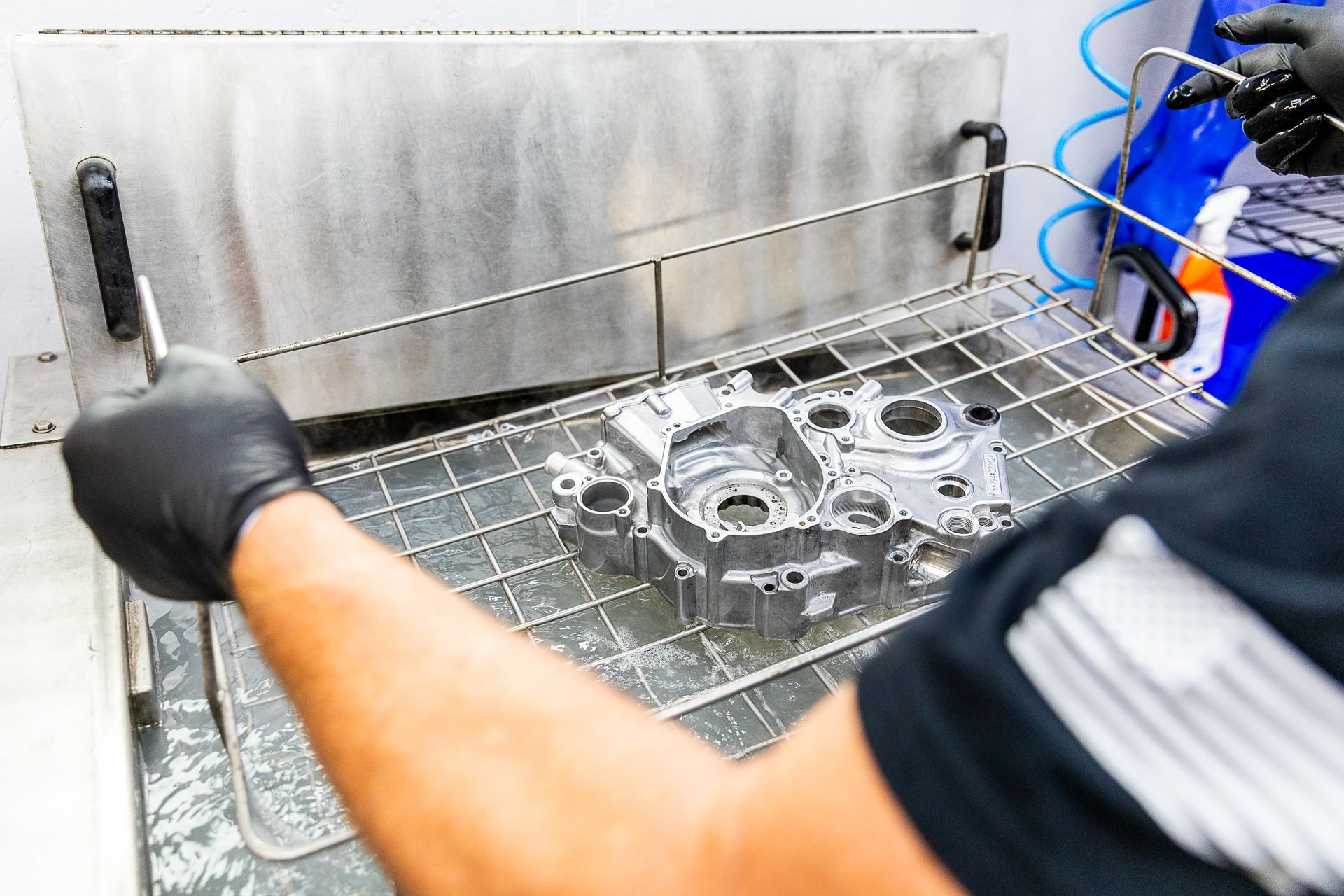 A man is cleaning a piece of metal in a machine.