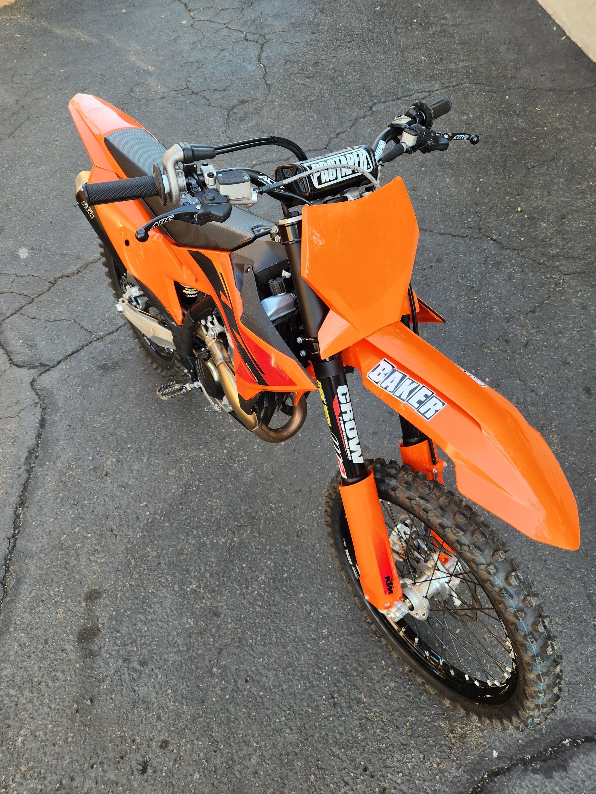 An orange dirt bike is parked on the side of the road
