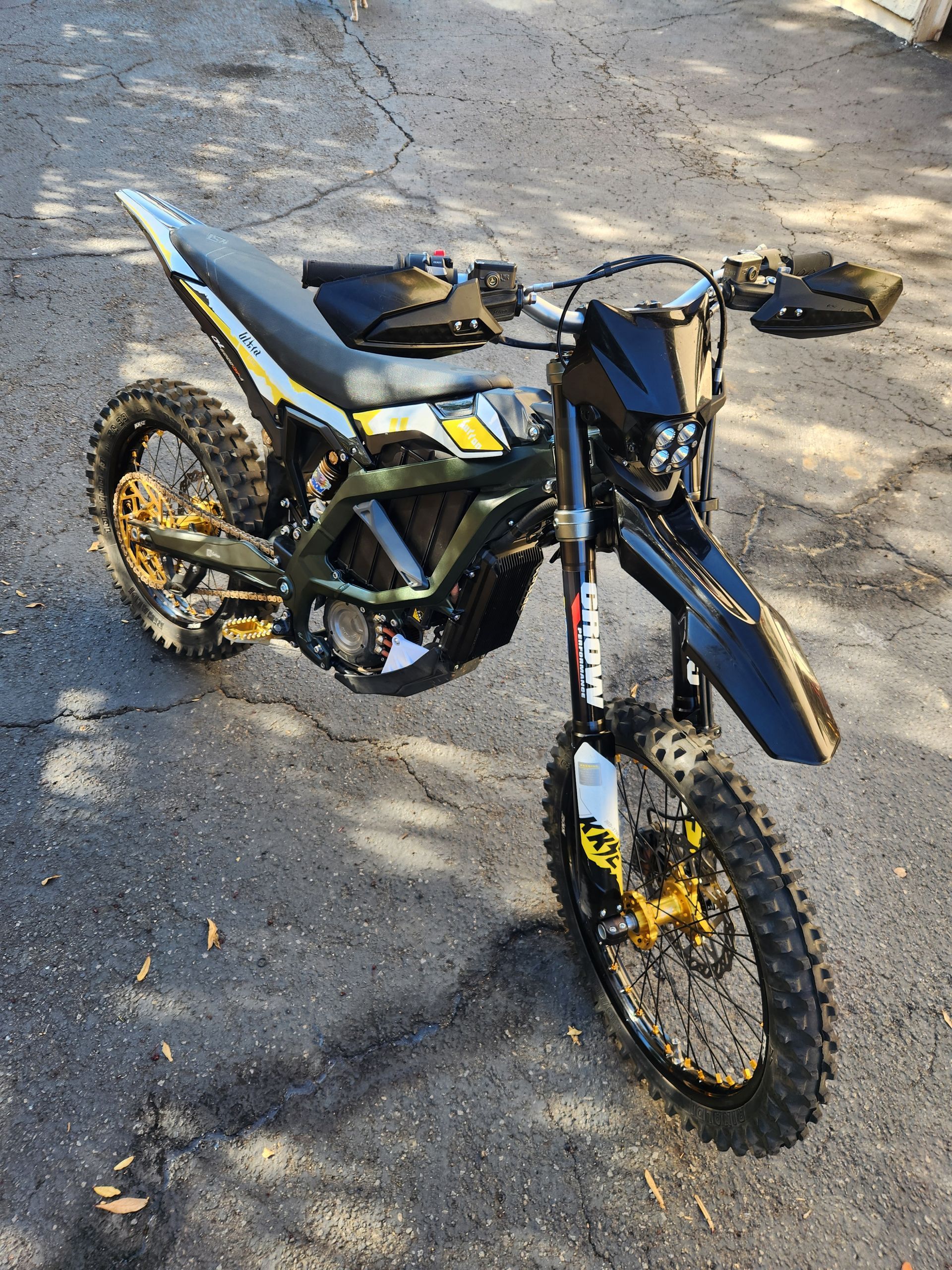 A black and yellow dirt bike is parked on the side of the road.