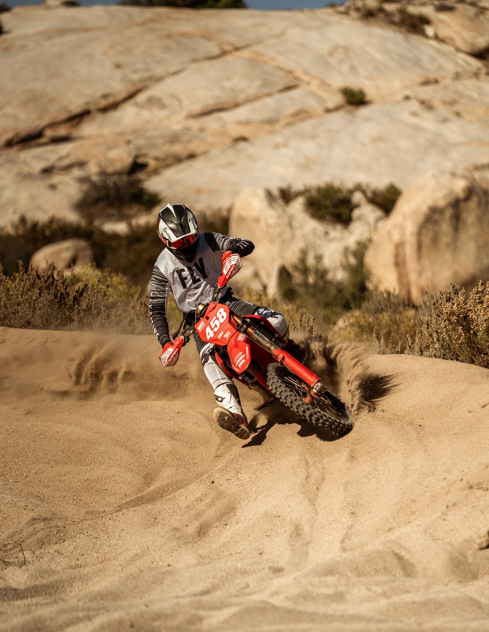A man is doing a trick on a dirt bike on a road.