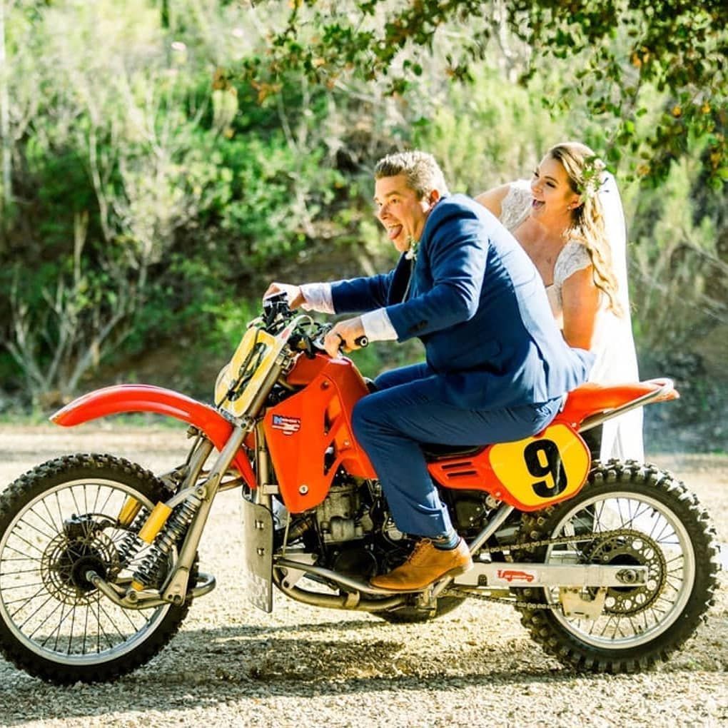 A bride and groom are posing for a picture on a dirt bike.
