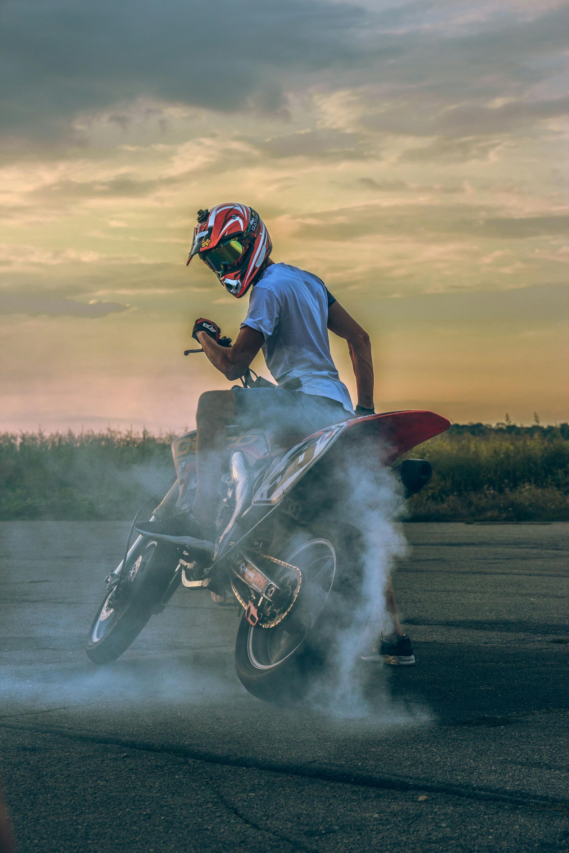 A man is doing a trick on a dirt bike on a road.