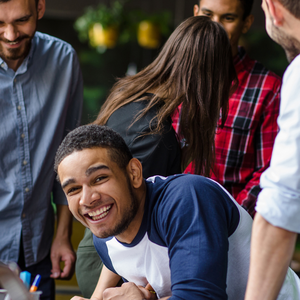 A man in a blue and white shirt is smiling in front of a group of people