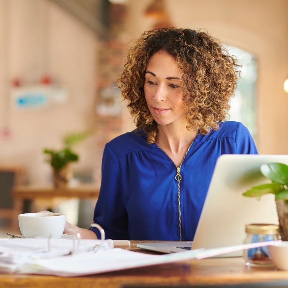 A woman is sitting at a table using a laptop computer.