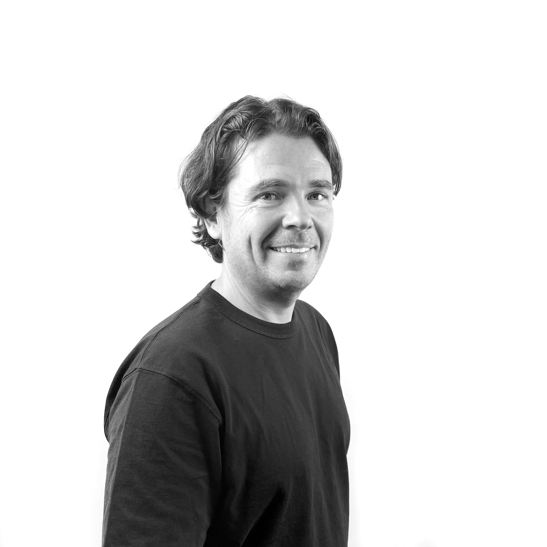 A man in a black shirt is smiling in a black and white photo