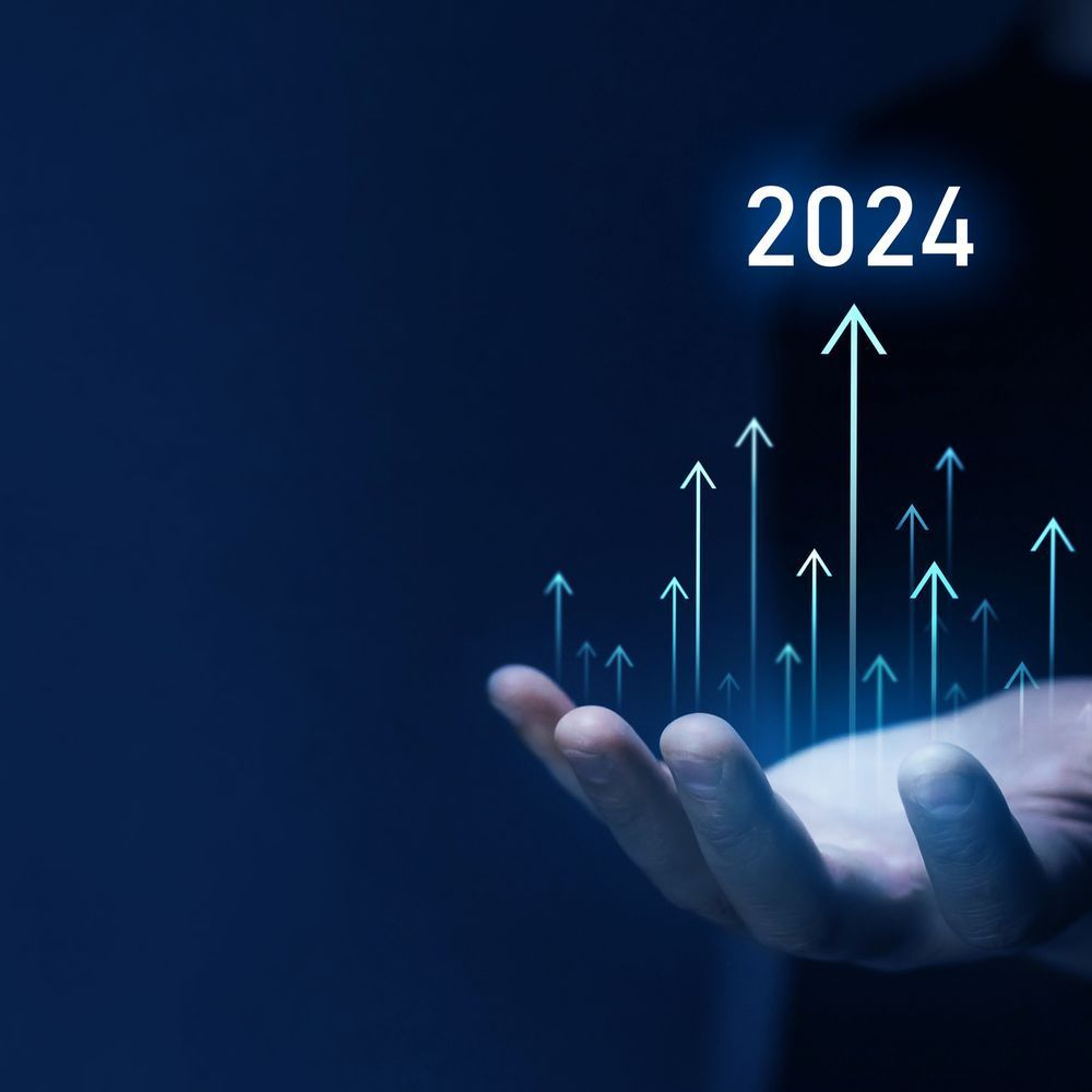 A hand is holding a graph with arrows pointing up and the year 2024.