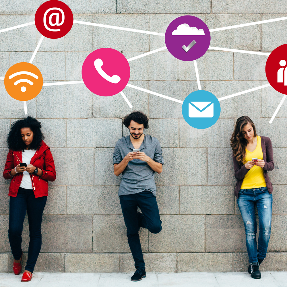 A group of people standing in front of a wall looking at their phones