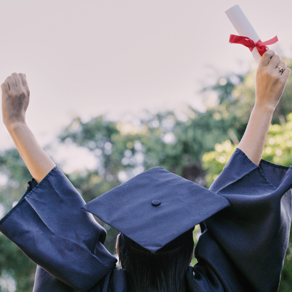 A woman in a graduation cap and gown is holding a diploma