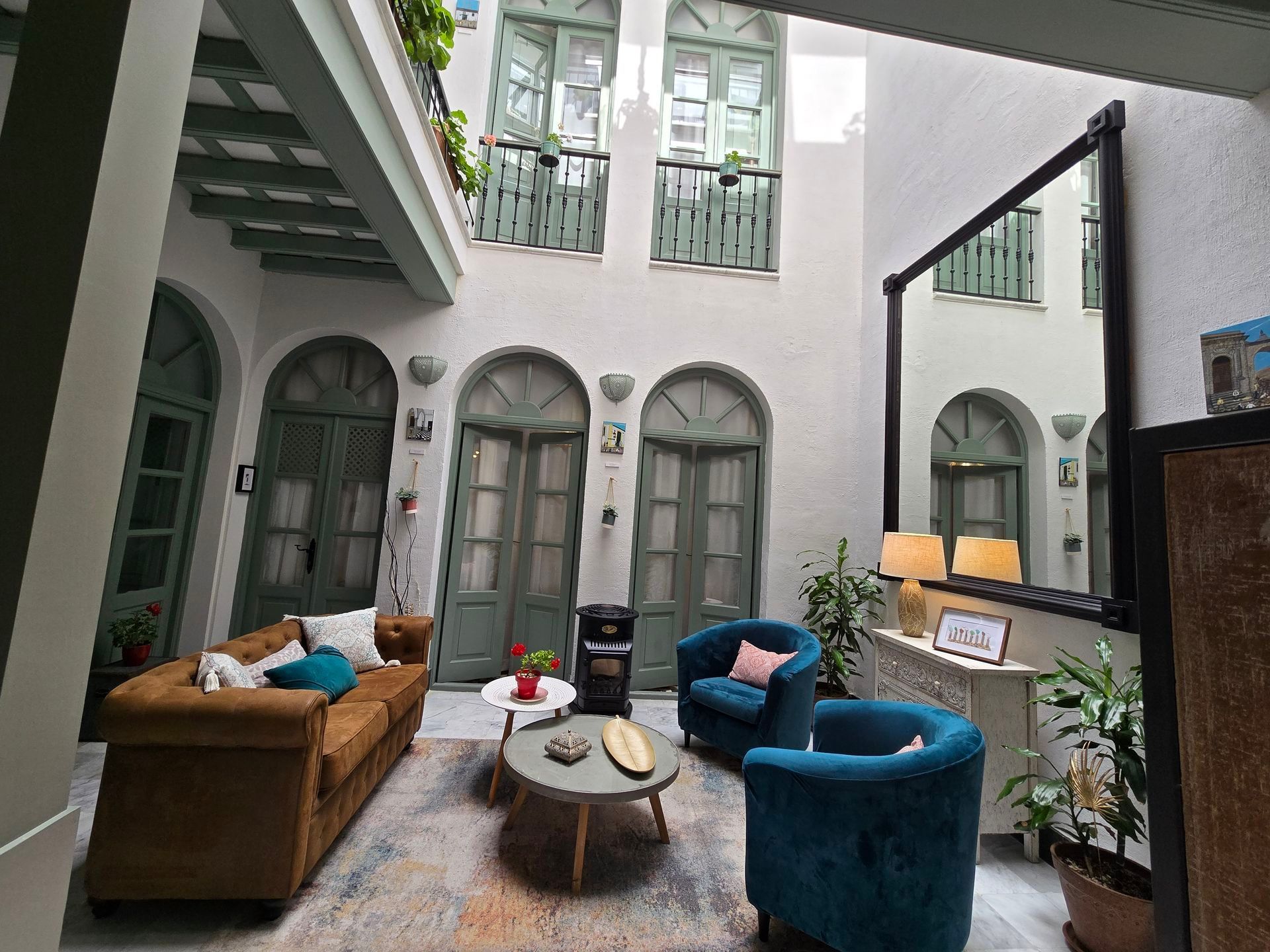 Un patio exterior con asientos: un sofá marrón, dos sillas azules y una pequeña mesa redonda. 