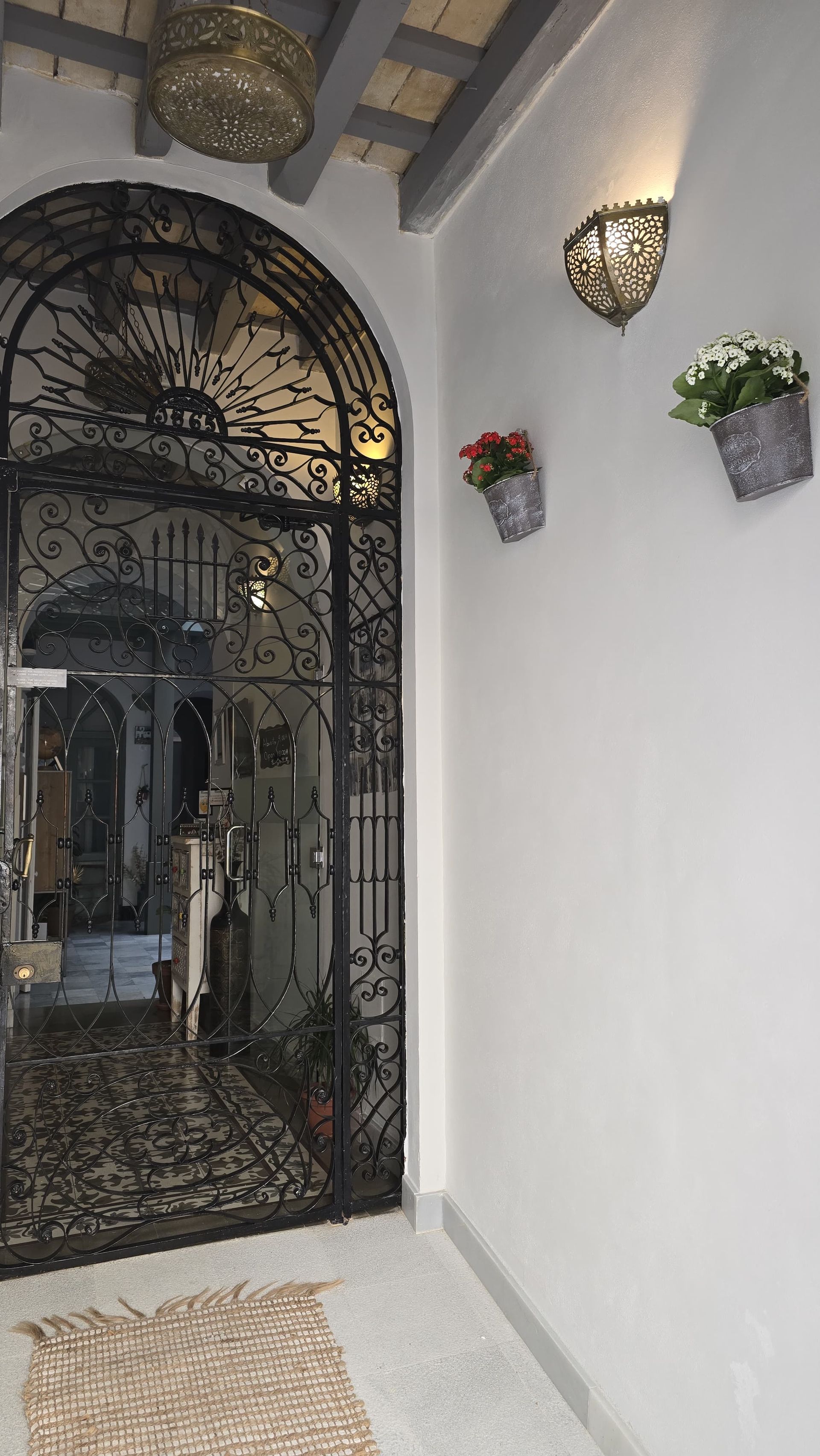 Patio con un sofá marrón, sillones azules y puertas verdes. Un gran espejo refleja el espacio.