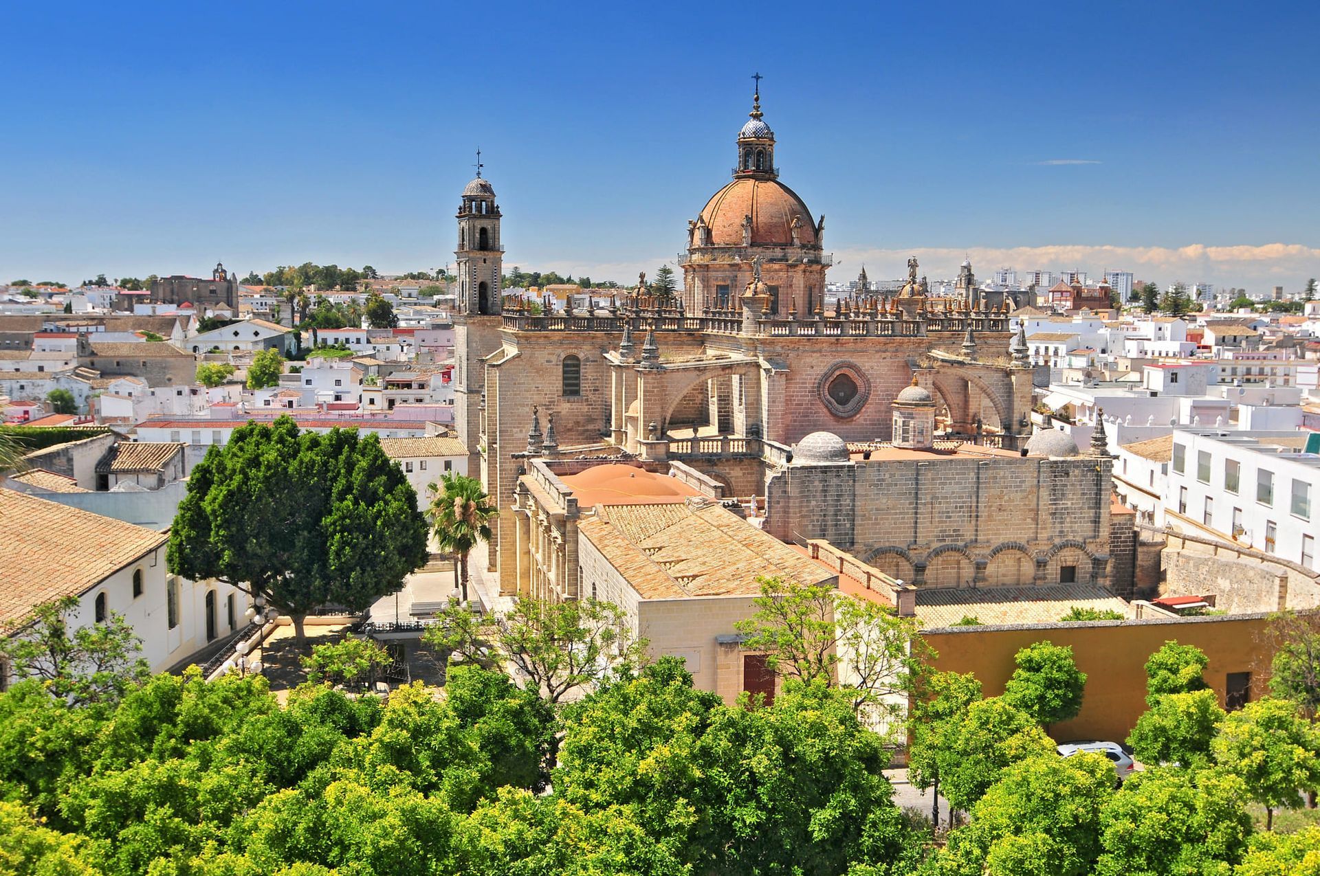 Iglesia con gran cúpula y torres en una ciudad de paredes blancas bajo un cielo azul.