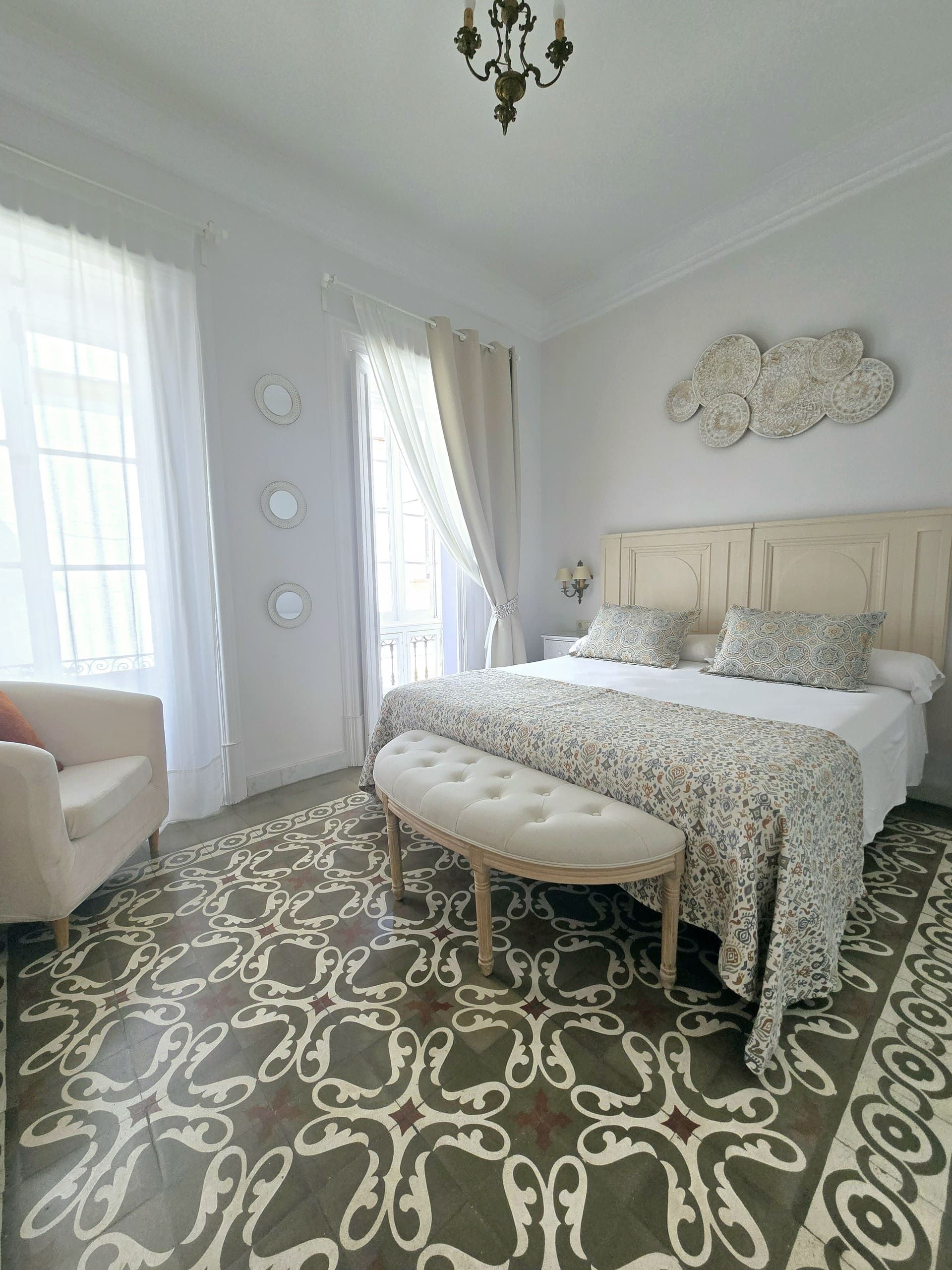 Elegante dormitorio con suelo, cama, asientos y detalles decorativos estampados.