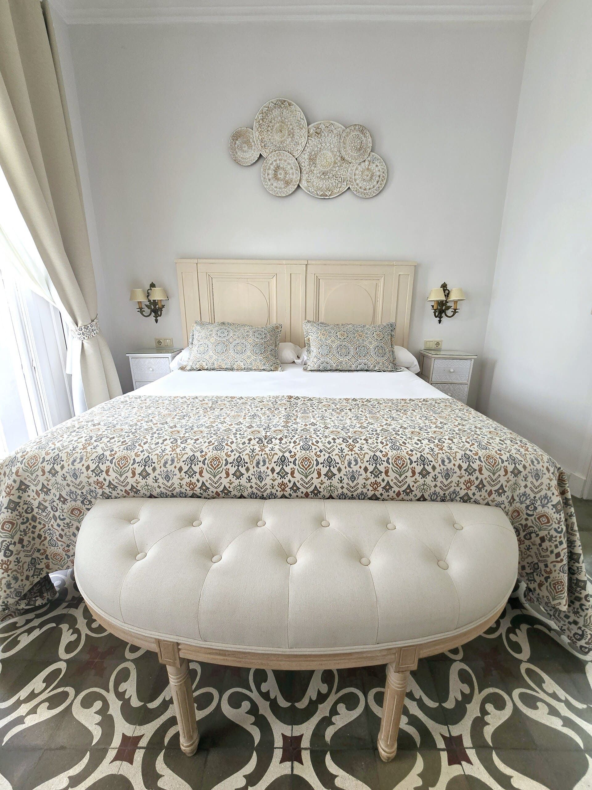 Dormitorio con cama, colcha estampada, banco acolchado y decoración de nubes.