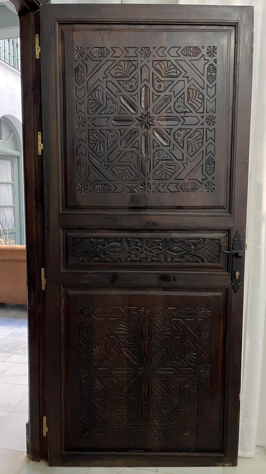 Puerta de madera oscura con intrincados paneles y tallas geométricas.