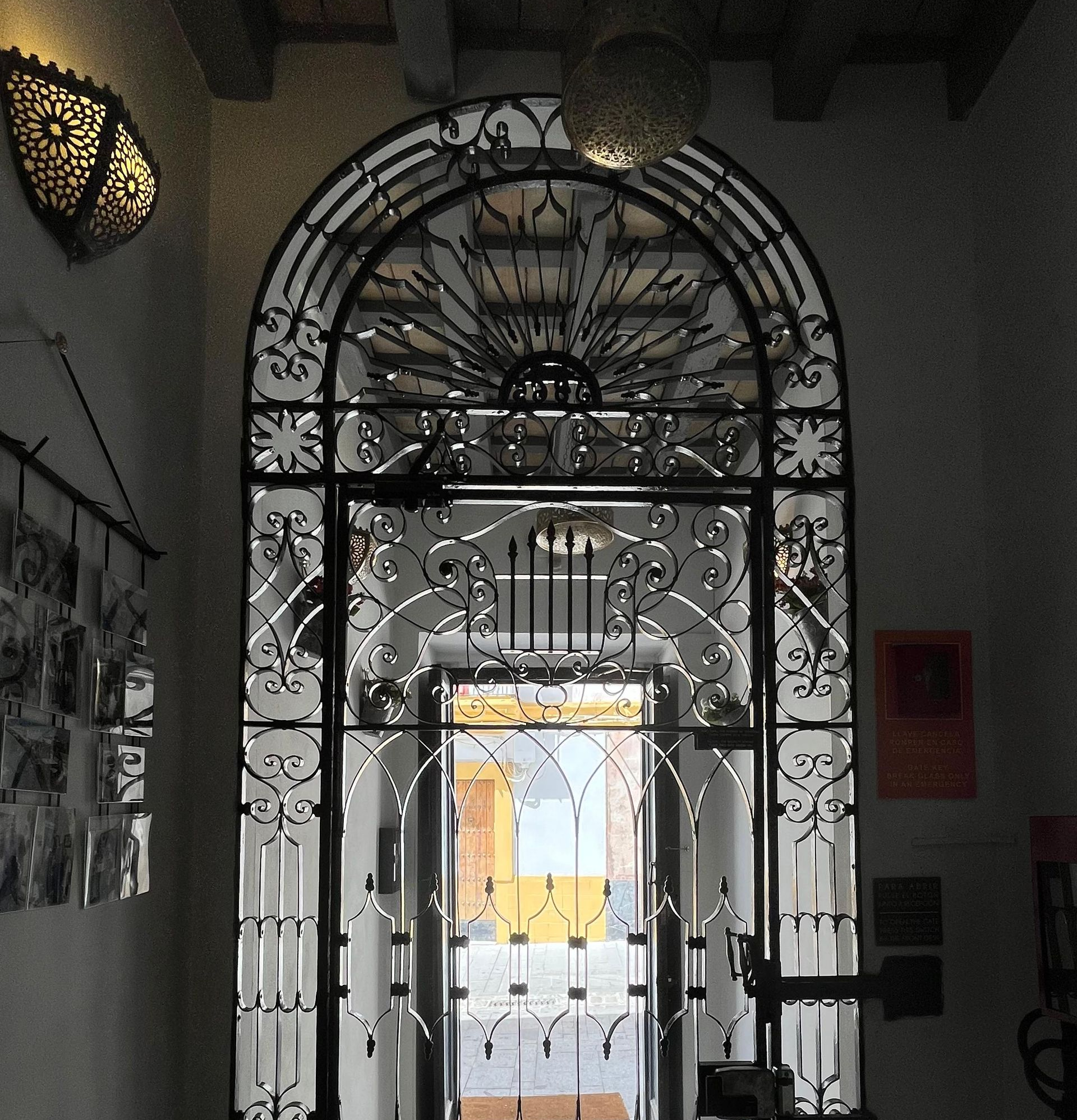 Patio con un sofá marrón, sillones azules y puertas verdes. Un gran espejo refleja el espacio.