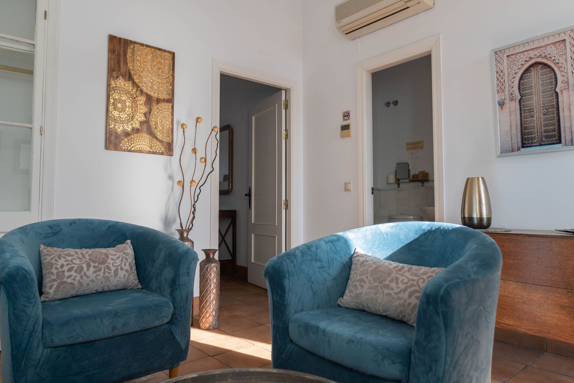 Dos sillones verde azulado en una sala de estar, con arte y puertas.