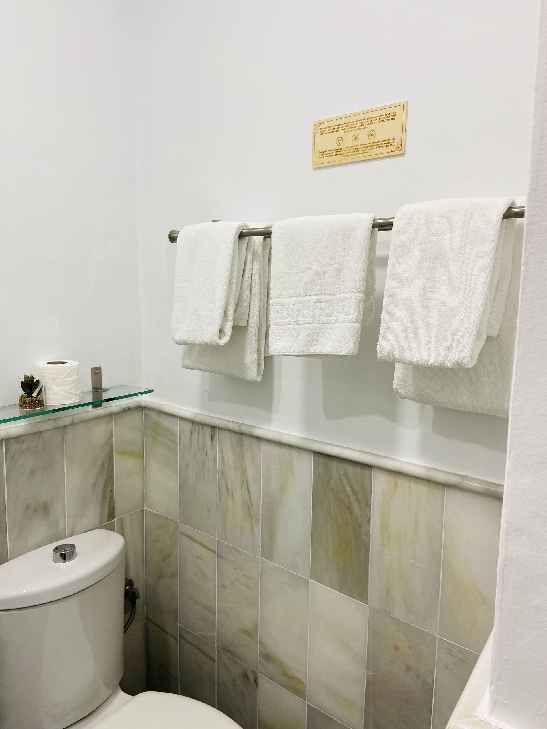 Toallas blancas colgadas en un toallero en un baño. 