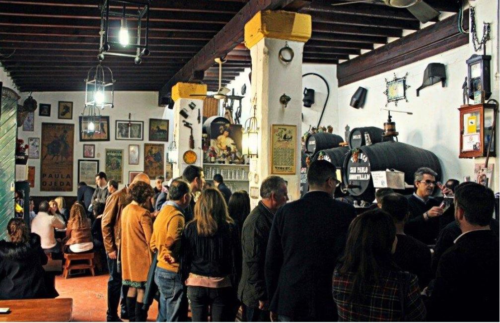 La gente se reunía en un bar abarrotado de estilo vintage, algunos en la barra, otros de pie. 