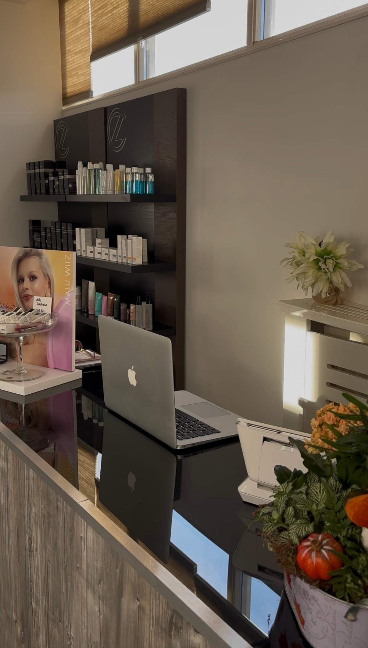 Receptiegedeelte met een zwarte balie, computer en producten uitgestald op schappen.