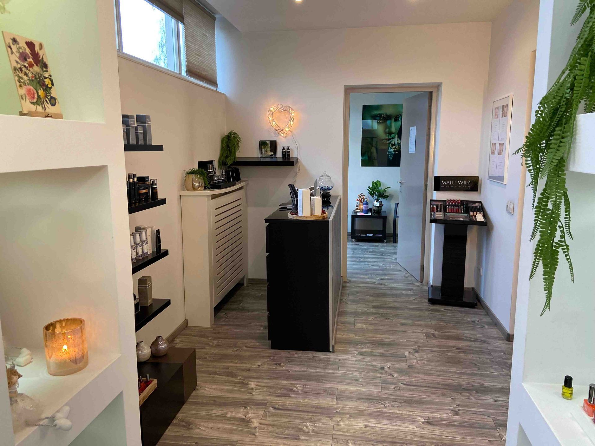 Interieur van een schoonheidssalon met producten uitgestald op planken en een receptiebalie.
