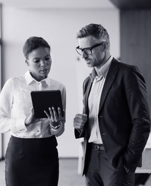 Woman and man reviewing a tablet. Woman points, man looks on, likely in an office setting.