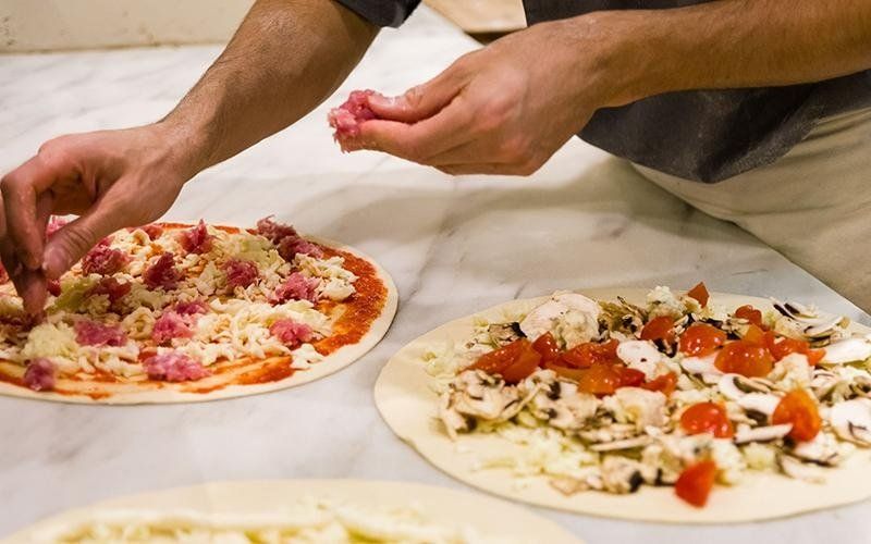 pizzaiolo farcisce pizze