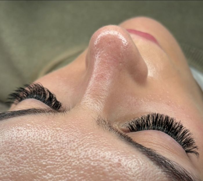 Hands giving a back massage; person lying face down, covered in oil, on a massage table.