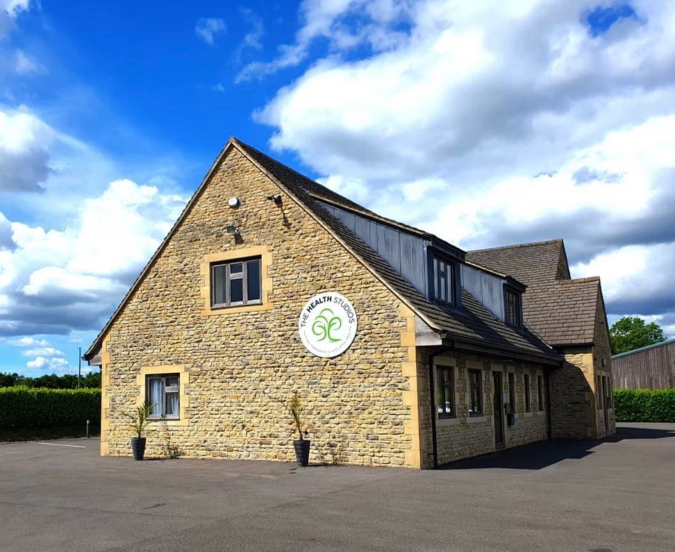 Stone building with a logo, under a blue sky with clouds.