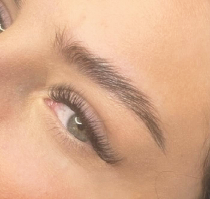 Woman receiving massage with oil, surrounded by lights and flowers.