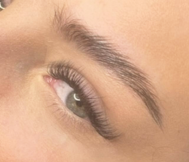 Woman receiving a facial massage at a spa; hands gently pressed on her face, eyes closed.
