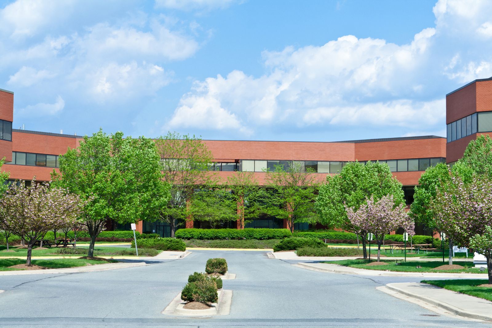 Brick office building with a curved design, trees, and a blue sky. Brick office building with a curved design, trees, and a blue sky.