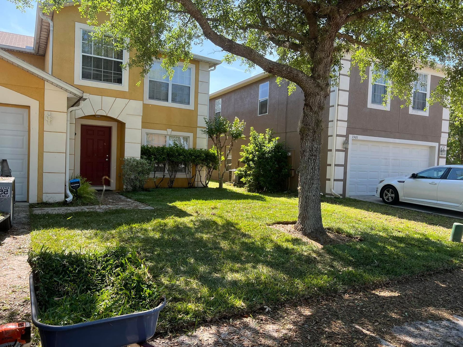 Two-story houses with green lawns. One is yellow, the other brown, with a tree in front.