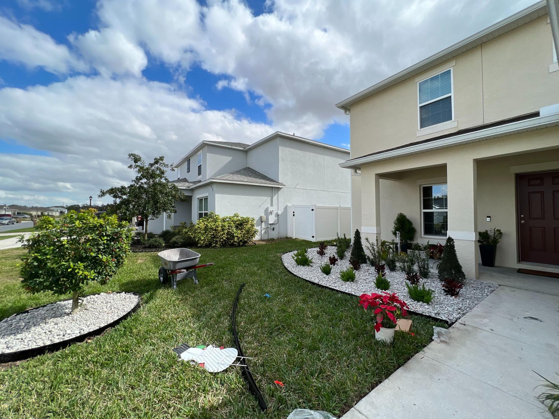 House exterior with landscaped yard featuring a curved flower bed and white gravel. Green grass, blue sky.