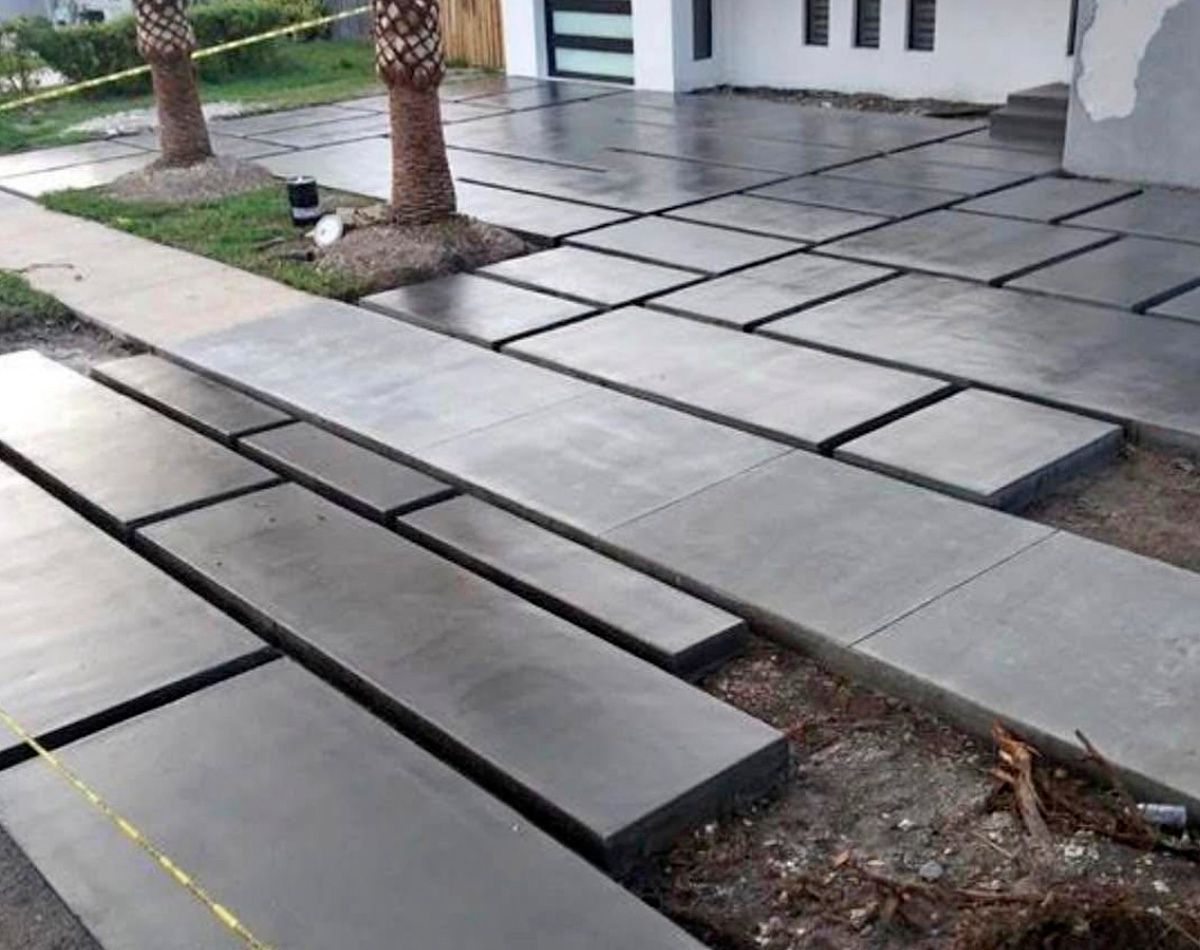 Concrete slabs forming a driveway and sidewalk. Gray concrete, rectangular shapes, outdoor setting.