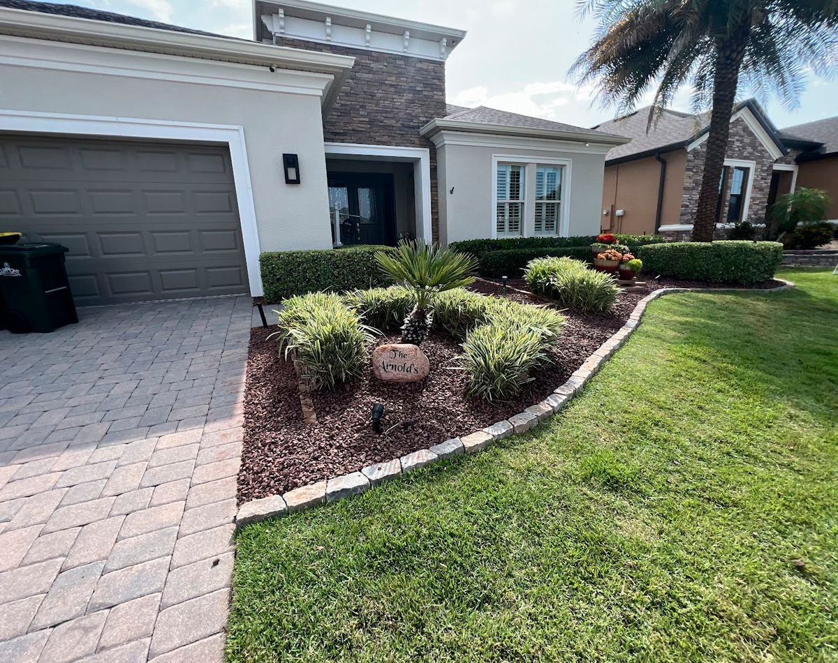 Front view of a house with a neatly landscaped yard and a brick driveway.