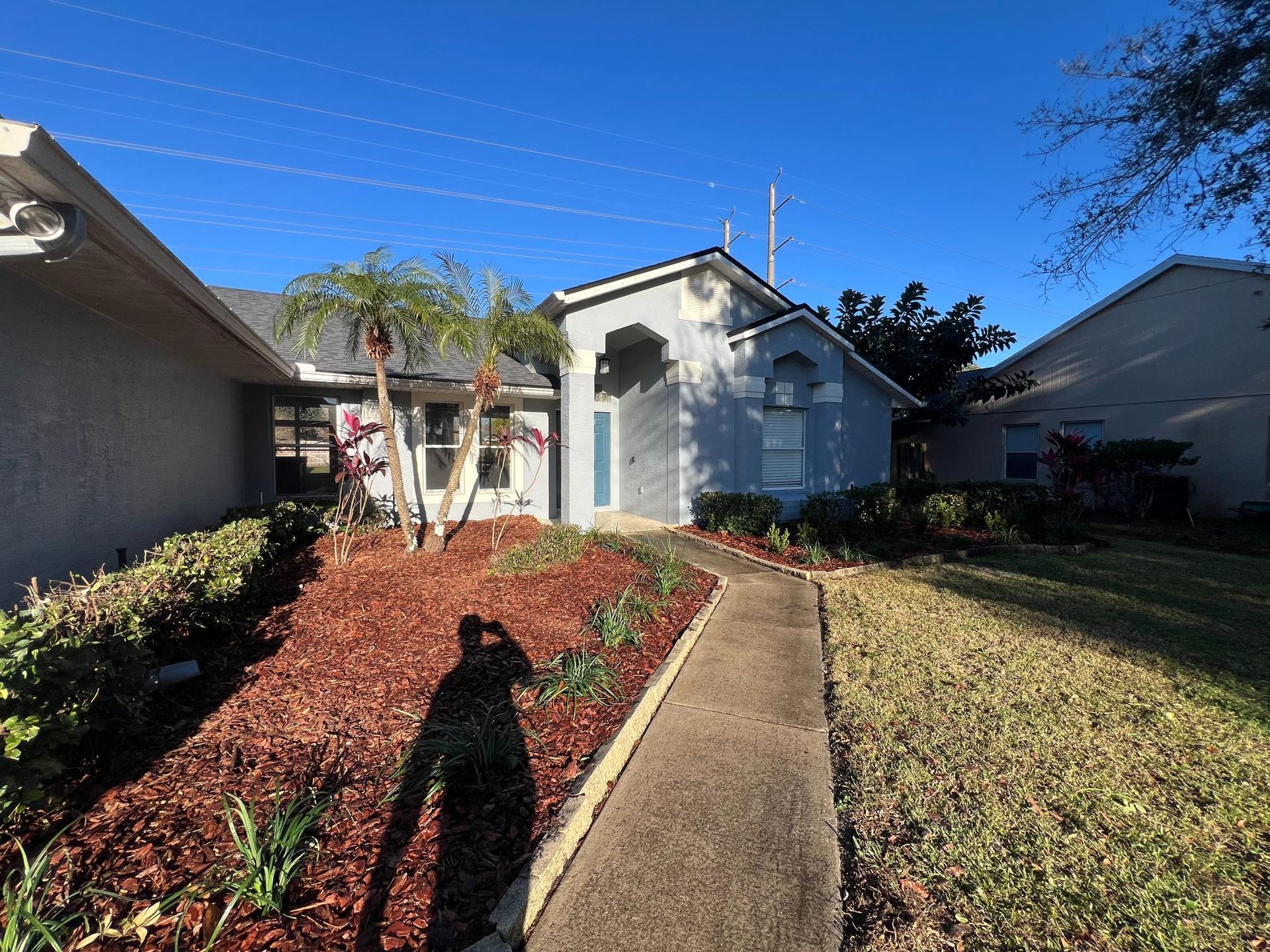 House exterior with a pathway, landscaping, and a blue sky.