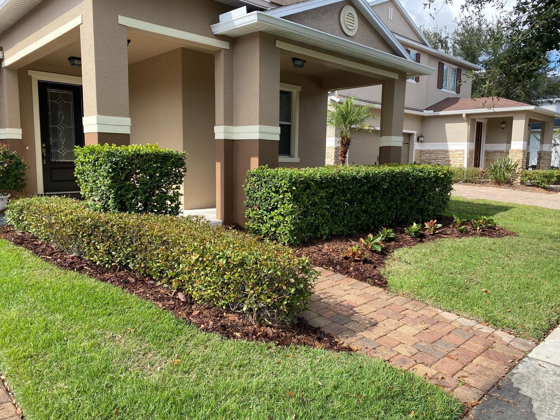 House exterior with manicured landscaping, brick walkway, and green lawn.