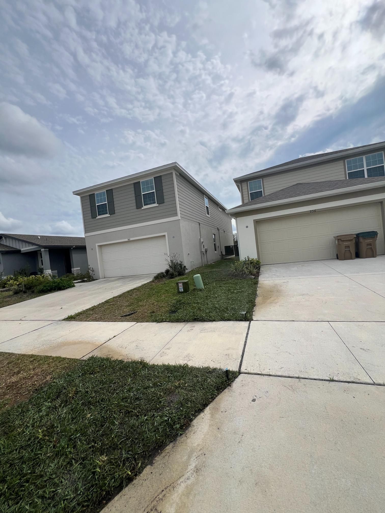 Two-story houses with attached garages and driveways. Cloudy sky above.