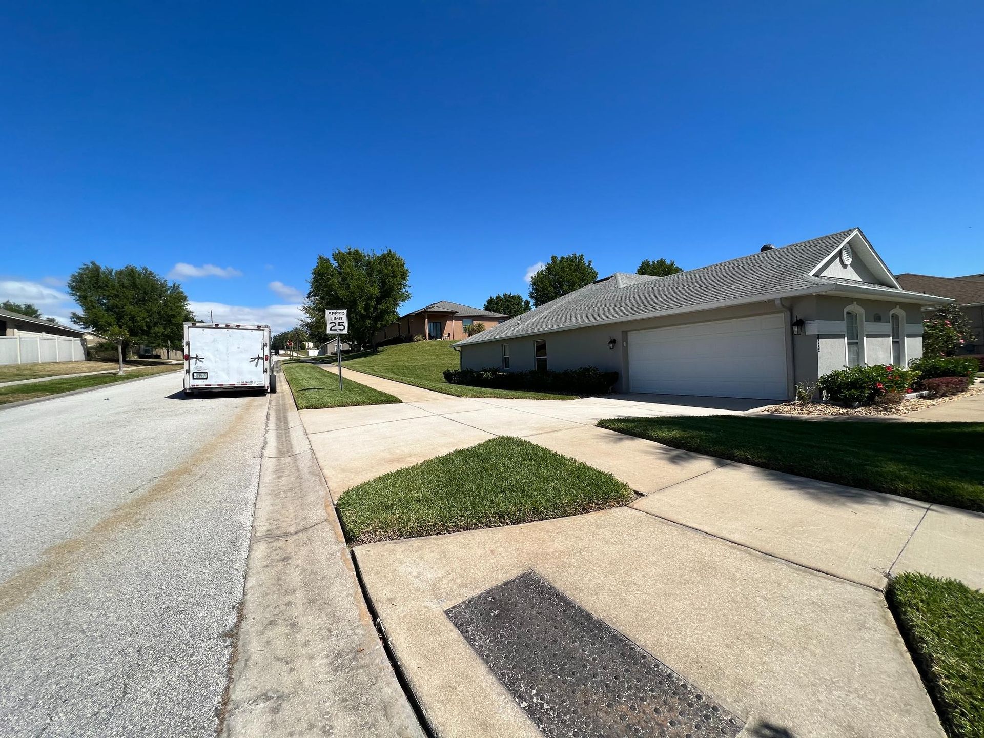 White van on road near suburban house under a blue sky.