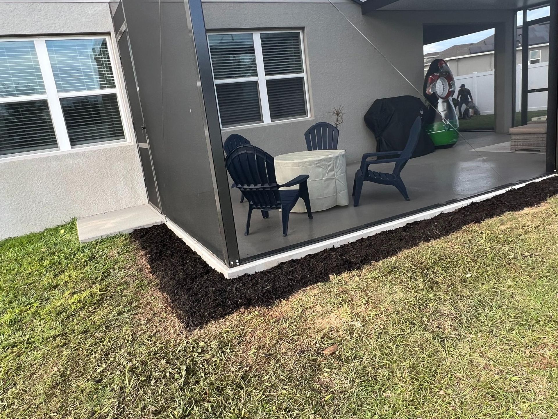 Patio with seating, mulch border, and grass.