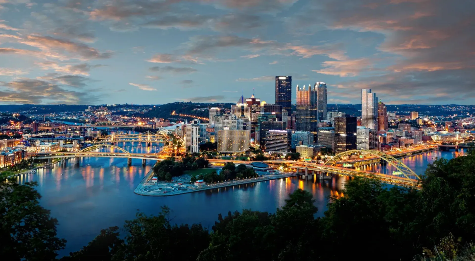 Aerial view of a city skyline with a river and bridges at dusk at The Alden South Hills in Pittsburgh, PA.