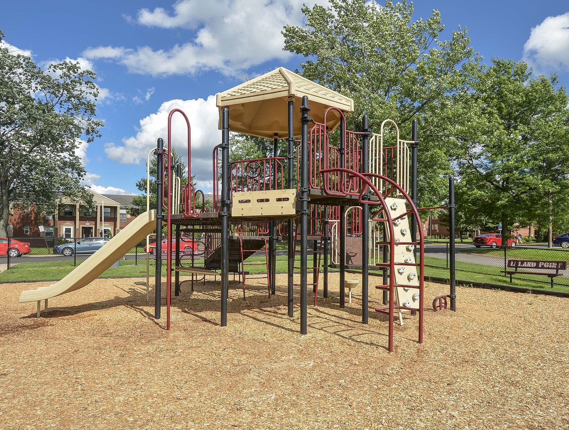 Playground with a slide and climbing structure at a residential complex on a wood-chip surface at The Alden South Hills in Pittsburgh, PA. 
