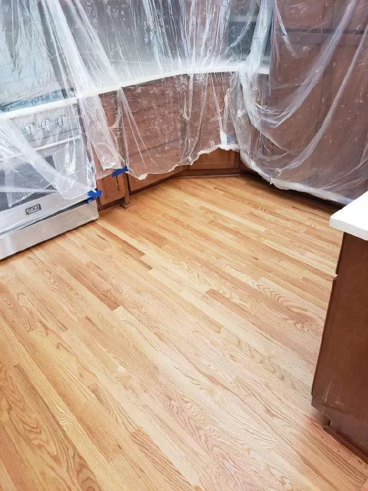 A kitchen with hardwood floors and cabinets covered in plastic.