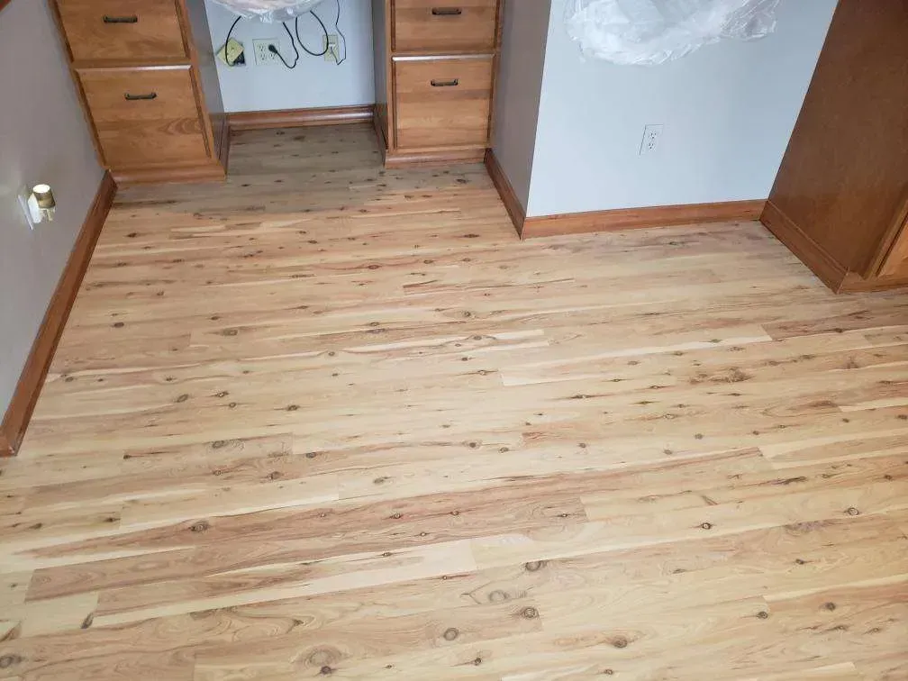 A wooden floor in a room with a desk and drawers.